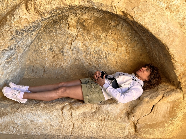       Person lying in a rock formation.
  