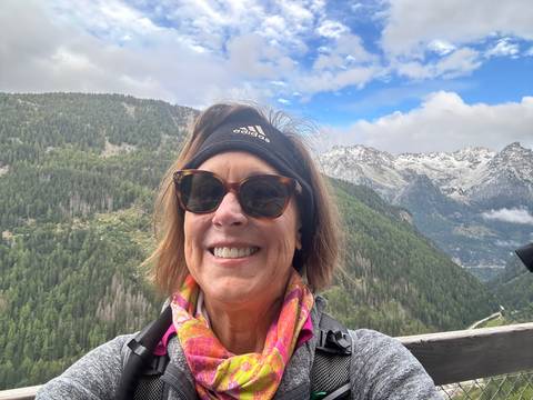       Person posing at a scenic viewpoint with mountains.
  