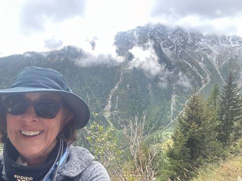       Person smiling in a mountain landscape setting.
  