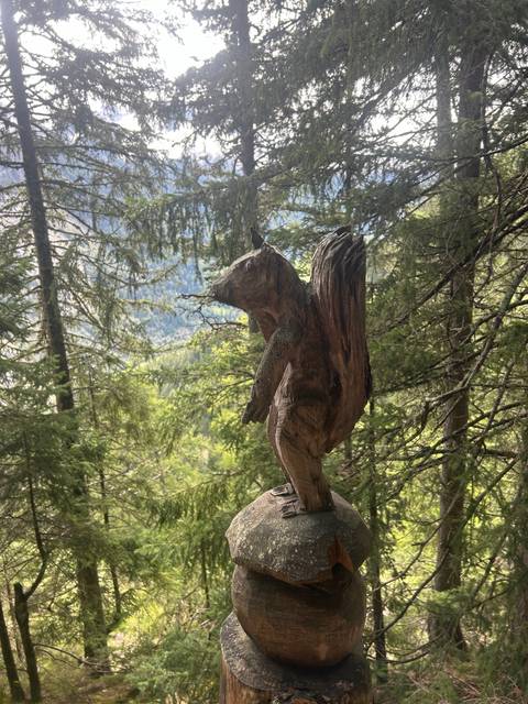       Wooden sculpture resembling a bird in a forest.
  