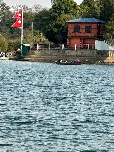 A lake with traditional architecture and mountains in the background.