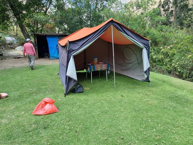       Campsite with a tent and colorful blanket.
  
