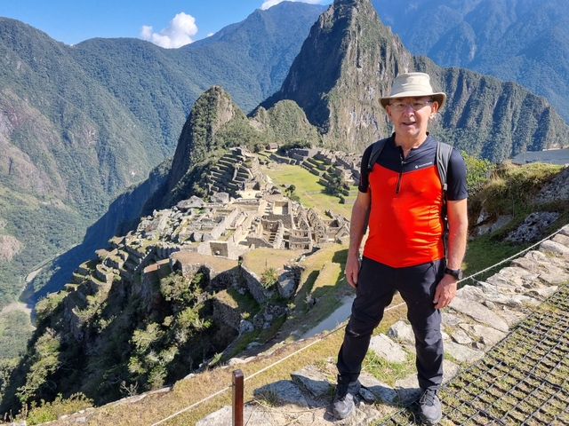       Man posing with a view of Machu Picchu behind him.
  