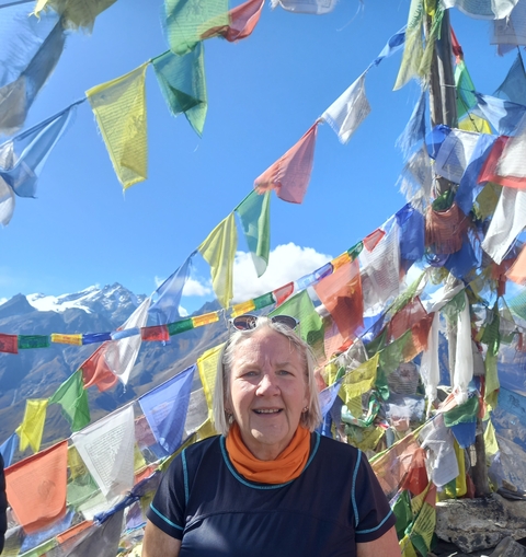 A person smiles in front of colorful prayer flags.