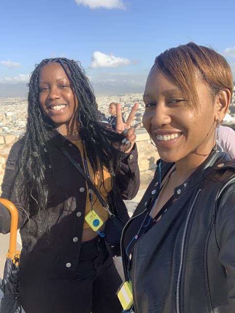 Two people smiling with a cityscape in the background.