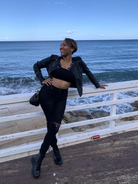 Person leaning against a railing with ocean view.