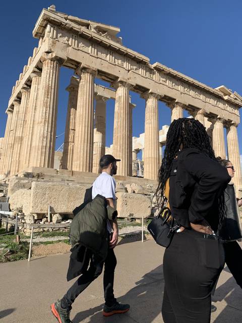 Two people walking near ancient ruins.