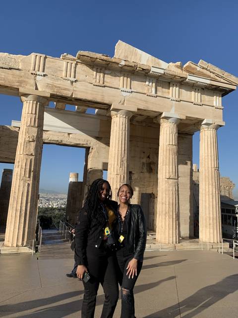 Two people smiling in front of ancient ruins.