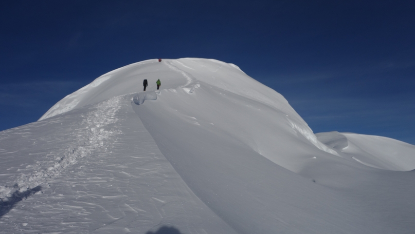 Climbers ascending snowy mountain ridge.