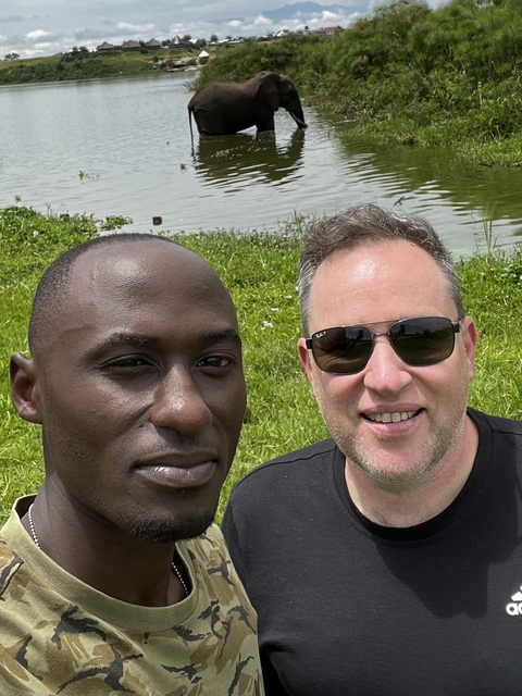       Two men smiling in outdoor setting.
  