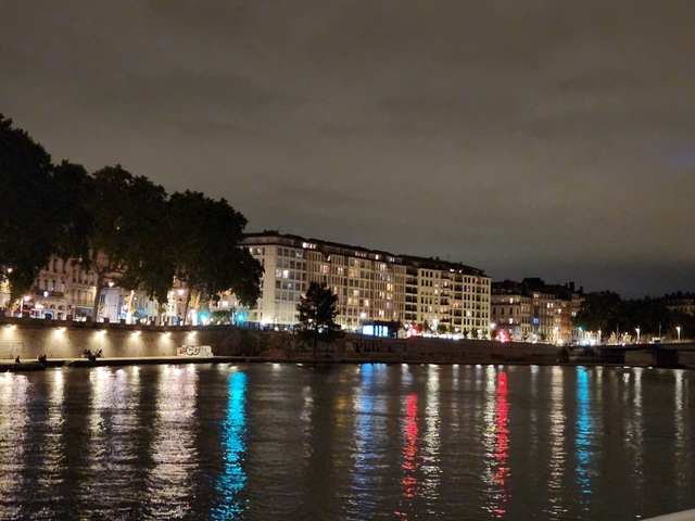 Buildings illuminated at night along a river.