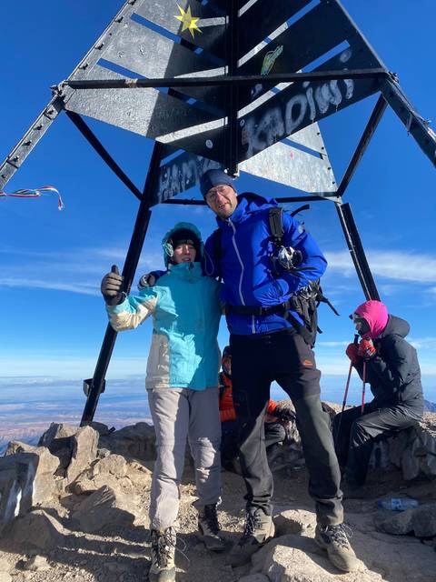 Tilted image of two people posing at a mountain summit.