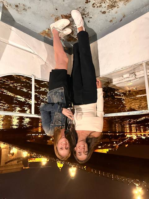 Two women posing on a boat at night.