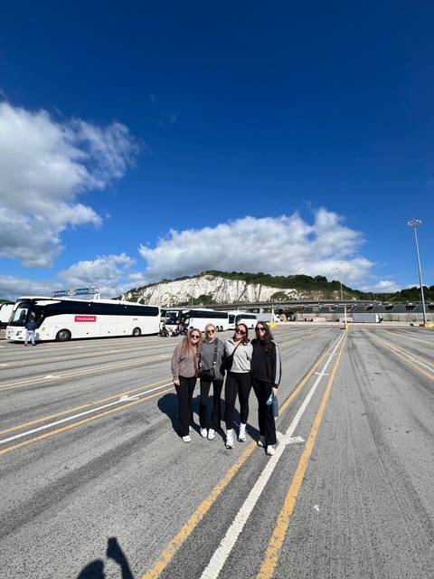 Group of friends posing on a ferry dock with white cliffs in the background.