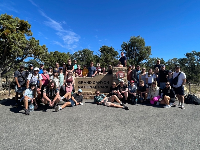 Group of people posing by a sign for Grand Canyon National Park.