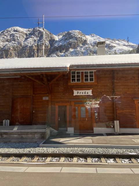       Train station sign and snowy mountain background.
  
