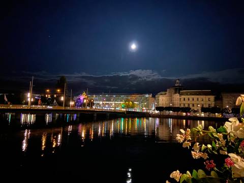       Night scene with lake and illuminated buildings.
  
