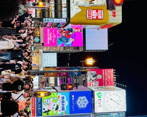 Colorful neon signs illuminate a bustling urban street at night.