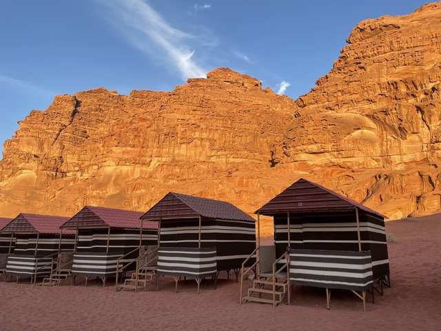 Row of traditional tents against a backdrop of red sandstone cliffs.