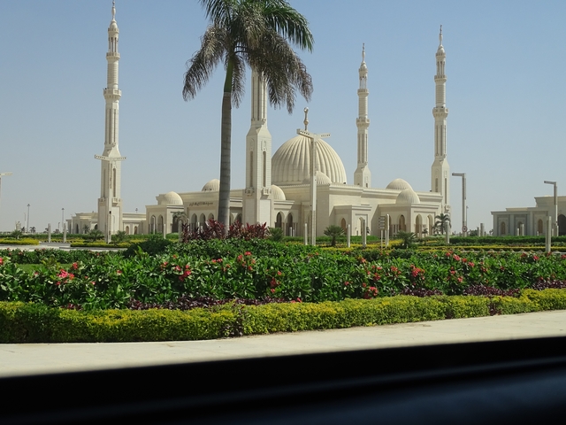       Beautiful mosque with white domes and minarets surrounded by gardens.
  