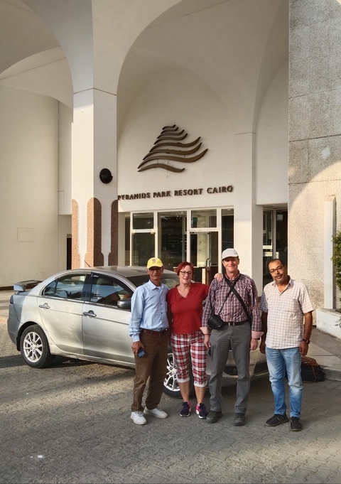       Group of people posing in front of Pyramids Park Resort Cairo.
  