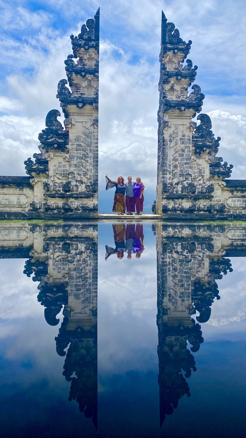 People posing in front of a Balinese gate with reflection.