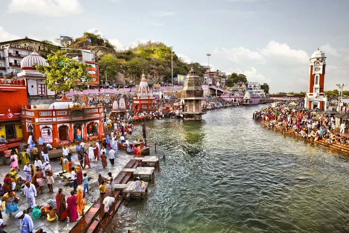 Vibrant riverside scene with people performing rituals.