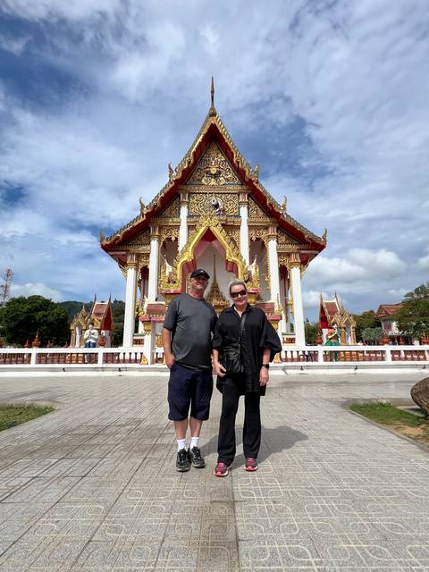       Tourists standing in front of a temple with ornate roofs.
  