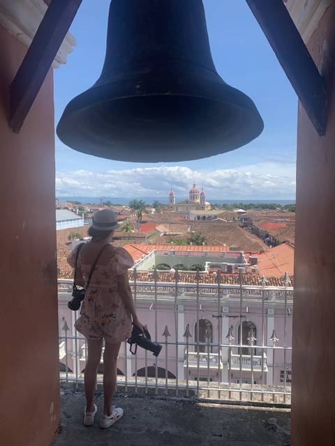 A person under an archway looking out at a city view with a colorful cathedral.