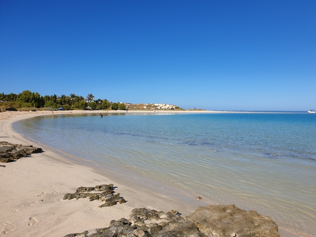       A tranquil beach with white sand and clear blue water.
  