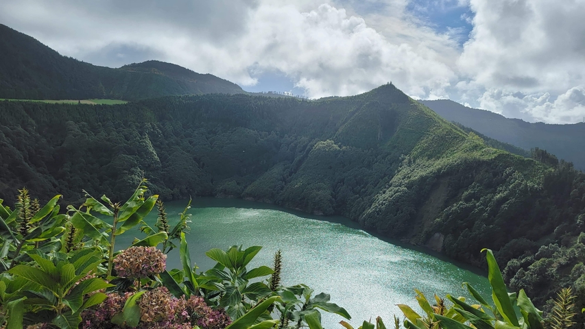       Lush green hills surrounding an emerald lake.
  
