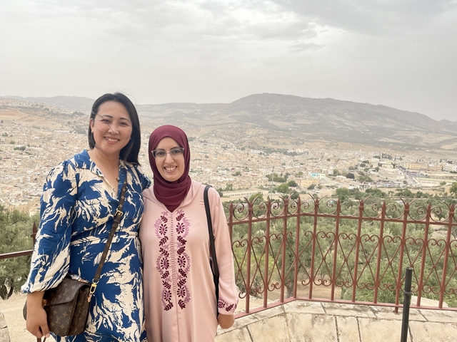       Women posing with a scenic city view.
  