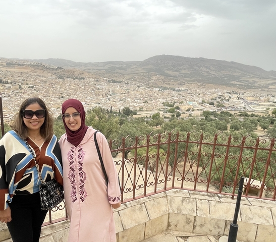 Two women with a city view in the background.