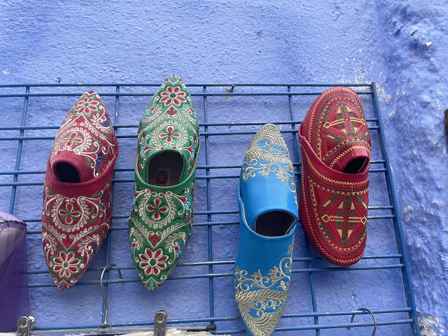       Colorful traditional shoes on display against a blue background.
  