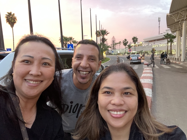       Three people smiling at an airport.
  