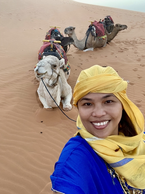 A woman with a camel in the desert.