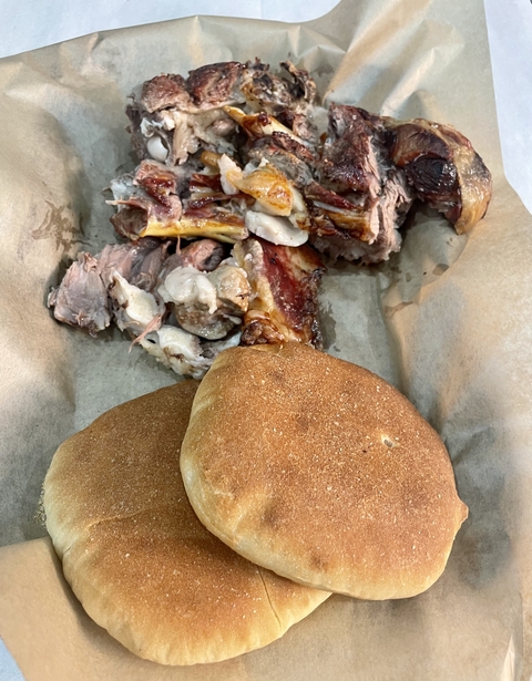       A dish with pieces of cooked meat and two loaves of bread.
  