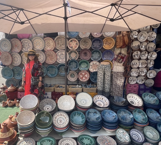       Person posing in front of a display of colorful ceramic plates.
  