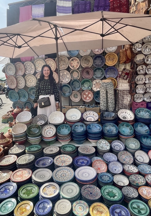 A person posing with a variety of colorful ceramic plates.