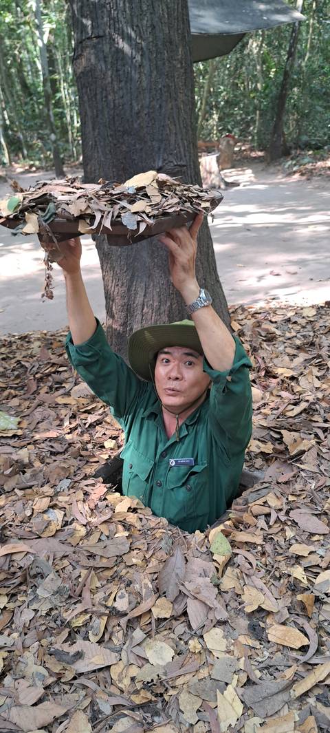 Person emerging from a forest floor surrounded by leaves.
