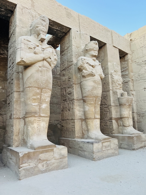       Close-up of ancient statues with hieroglyphs in the background.
  
