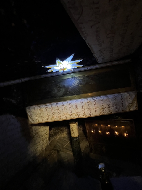       Dimly lit setting with religious inscriptions and decorations.
  