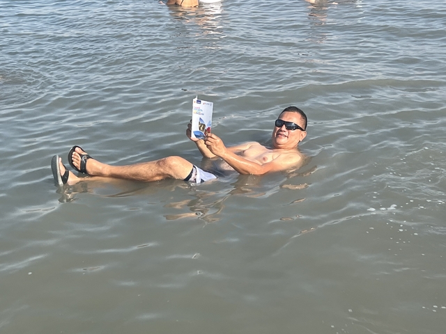       Person floating in water reading a brochure.
  