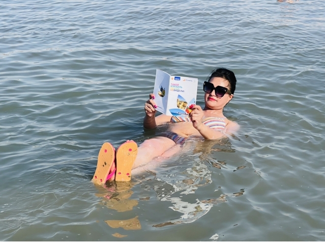       Person reading a magazine while floating in water.
  