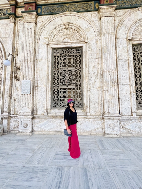 A person standing in front of an ornate building facade with decorative grille work.