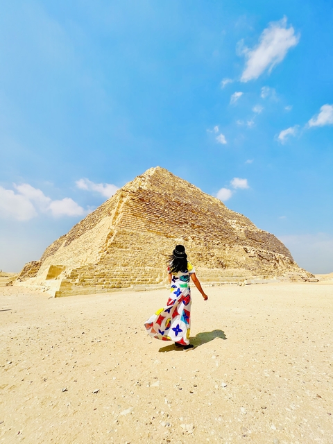 Person walking towards a large ancient pyramid.