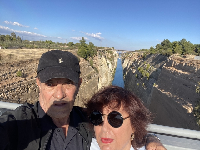       A couple in front of a scenic gorge with a bridge in the distance.
  