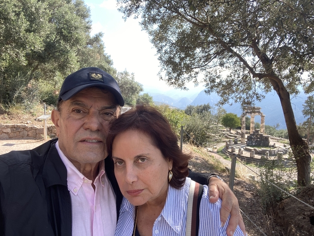       A couple standing in front of ancient ruins with mountains.
  