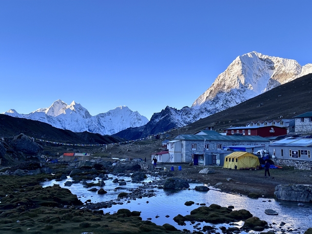       Village in the mountains with snow-covered peaks in the background.
  