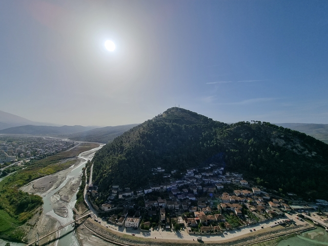 Hill with trees and a structure on the top viewed from a distance.